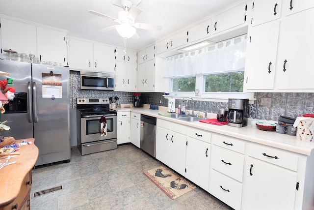 kitchen featuring appliances with stainless steel finishes, tasteful backsplash, ceiling fan, sink, and white cabinets