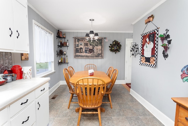 dining room with a chandelier, ornamental molding, and wood walls