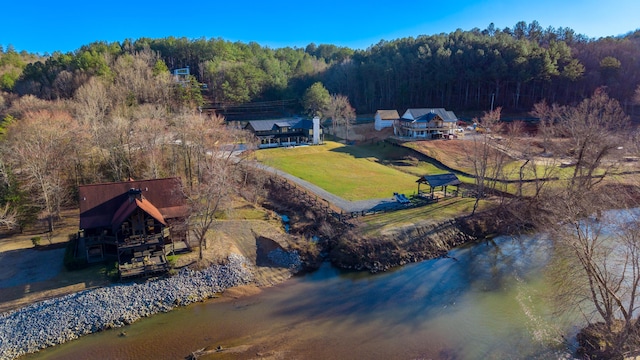 birds eye view of property featuring a water view and a wooded view