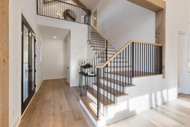 foyer featuring hardwood / wood-style flooring, a high ceiling, stairway, and baseboards