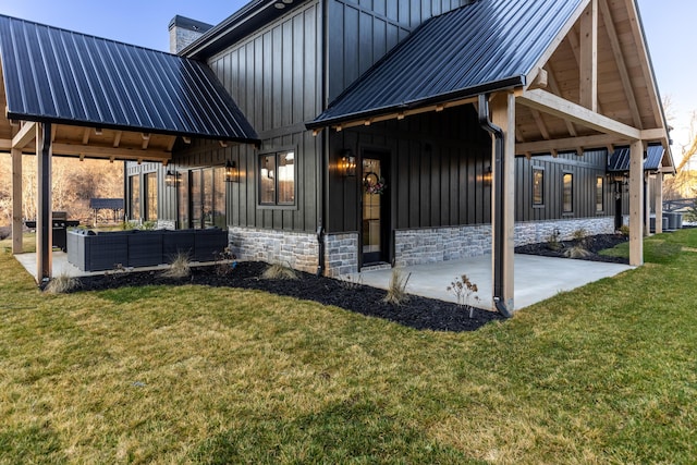 exterior space featuring board and batten siding, a lawn, an outdoor hangout area, a chimney, and a patio