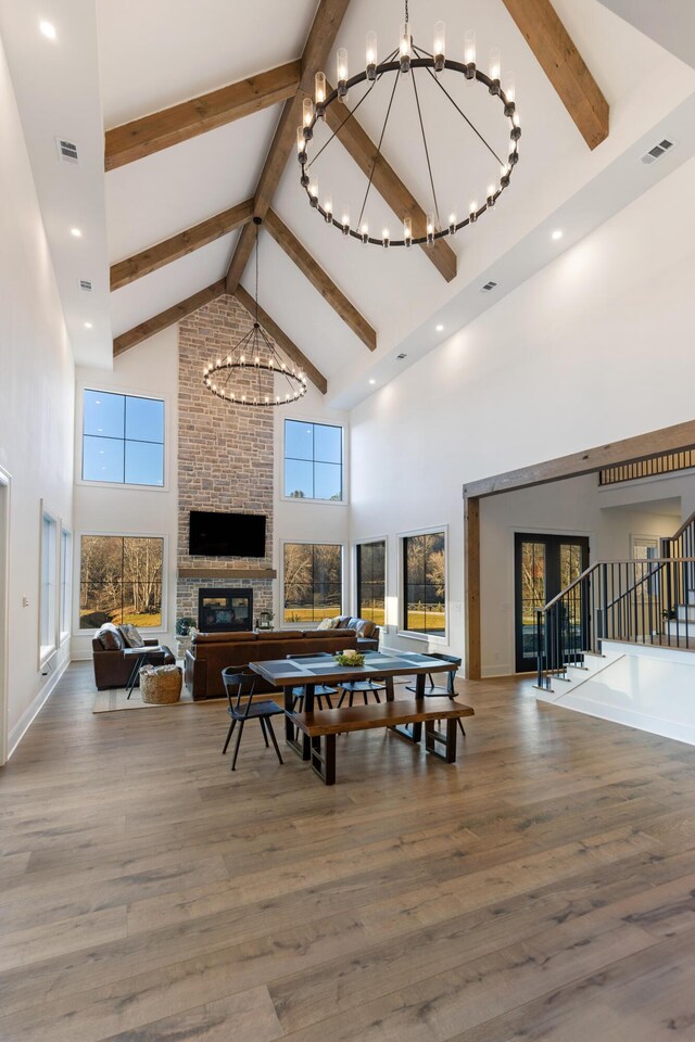 dining space with visible vents, a brick fireplace, an inviting chandelier, and wood finished floors