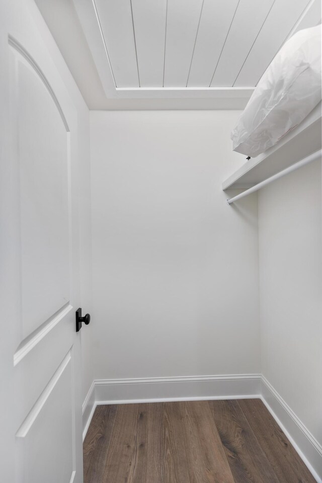 walk in closet with dark wood-style floors