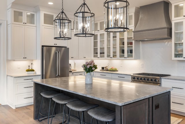 kitchen with white cabinetry, custom range hood, high end appliances, and a kitchen island