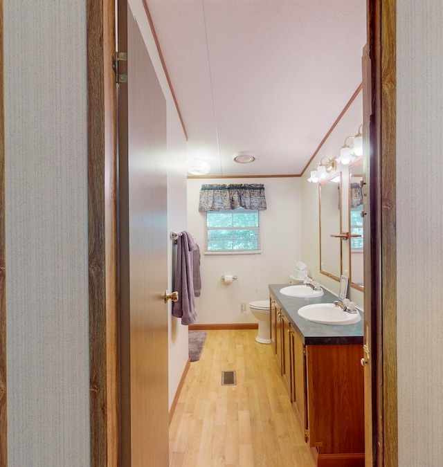 bathroom with hardwood / wood-style flooring, vanity, toilet, and crown molding