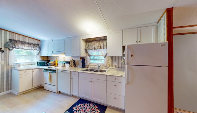 kitchen featuring a healthy amount of sunlight, white cabinetry, white appliances, and sink