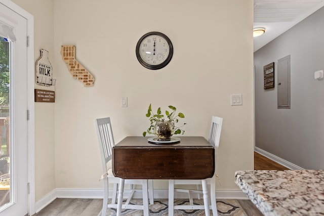 dining space with electric panel and hardwood / wood-style flooring