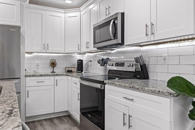 kitchen with backsplash, light stone counters, white cabinets, and appliances with stainless steel finishes