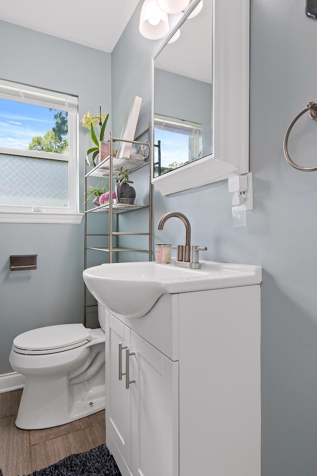 bathroom with hardwood / wood-style floors, vanity, toilet, and a wealth of natural light