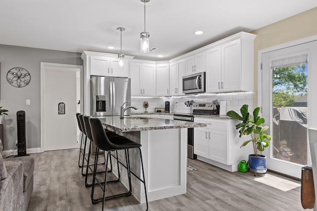 kitchen featuring light stone countertops, stainless steel appliances, white cabinetry, and light hardwood / wood-style floors