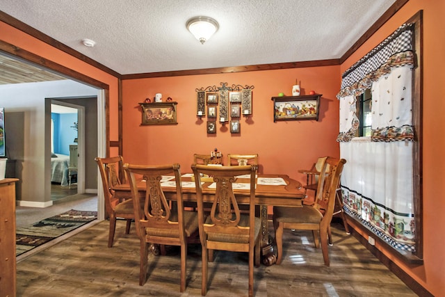 dining space featuring a textured ceiling, dark hardwood / wood-style flooring, and crown molding