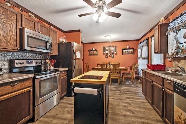 kitchen featuring ceiling fan, sink, dark wood-type flooring, backsplash, and appliances with stainless steel finishes