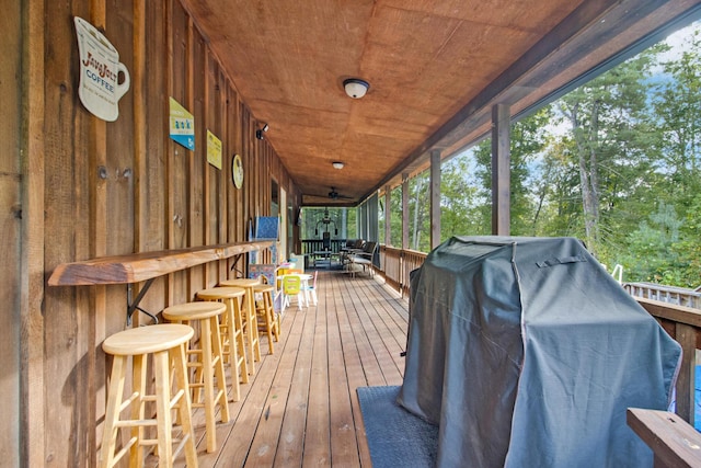 wooden terrace with an outdoor bar and a grill