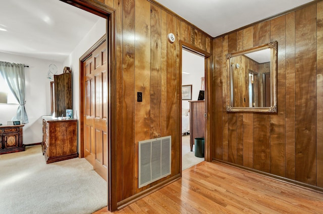 corridor featuring light carpet and wood walls