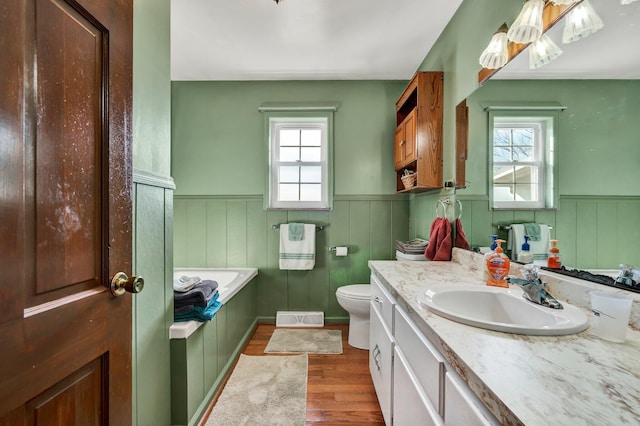 bathroom with vanity, a tub to relax in, hardwood / wood-style flooring, and toilet