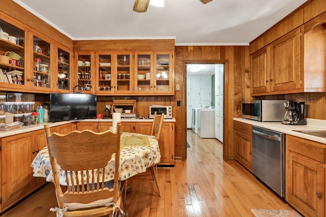 kitchen featuring crown molding, ceiling fan, stainless steel appliances, washing machine and clothes dryer, and light wood-type flooring