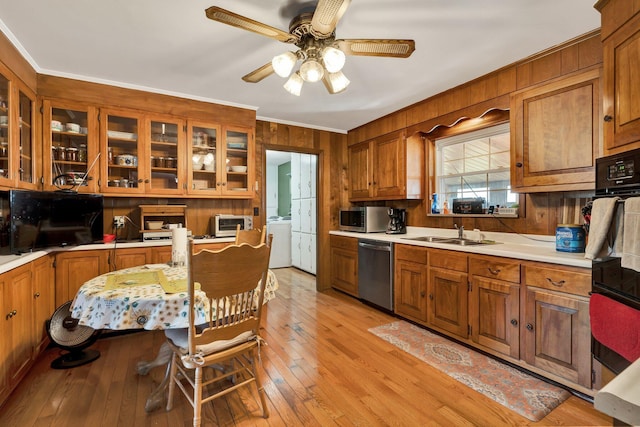 kitchen featuring appliances with stainless steel finishes, washer / dryer, sink, ornamental molding, and light wood-type flooring