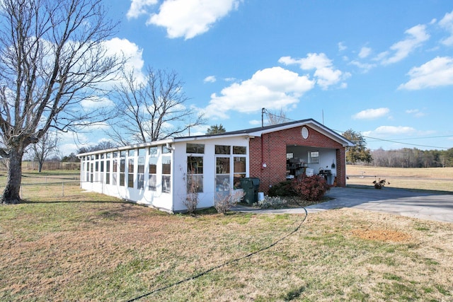 view of property exterior with a sunroom and a lawn