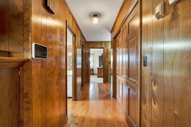 hall featuring wooden walls and light hardwood / wood-style floors