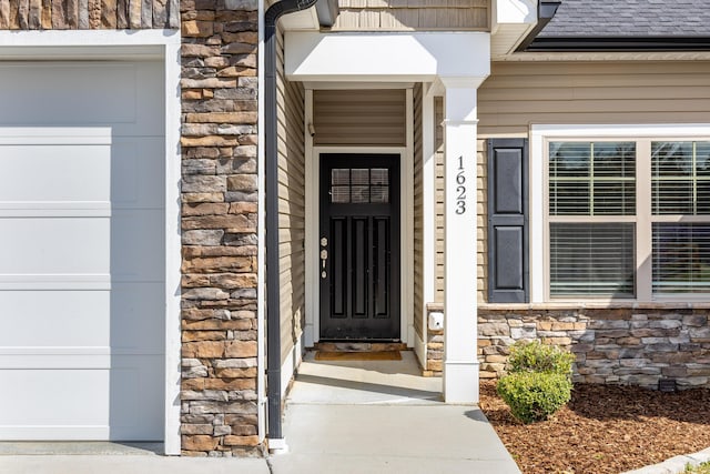 view of exterior entry featuring an attached garage, stone siding, and a shingled roof