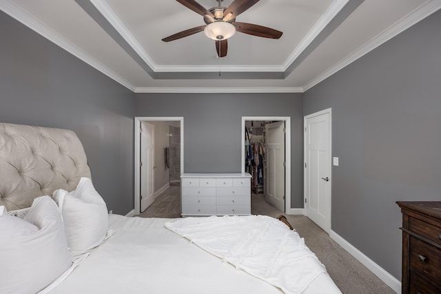 carpeted bedroom with baseboards, crown molding, a tray ceiling, and connected bathroom