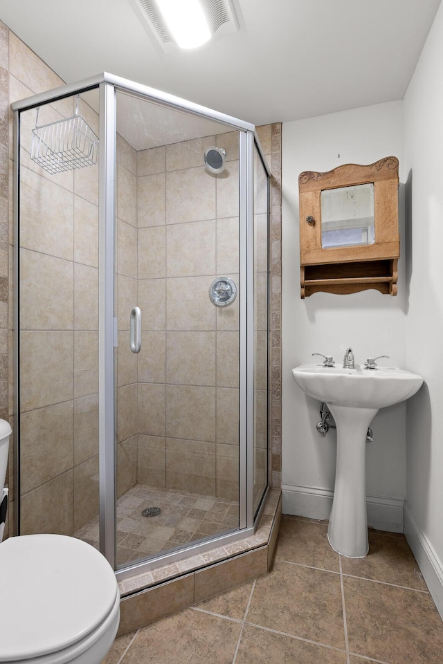 bathroom featuring a shower stall, toilet, and baseboards