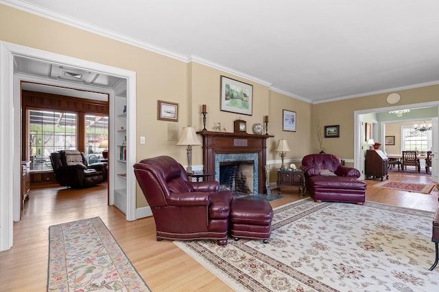 living area featuring a chandelier, ornamental molding, a high end fireplace, and light wood finished floors