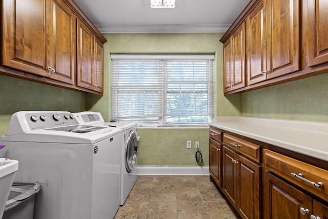 clothes washing area featuring stone finish flooring, baseboards, washer and clothes dryer, ornamental molding, and cabinet space