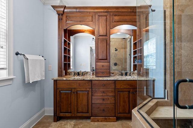 bathroom featuring a stall shower, crown molding, baseboards, and double vanity