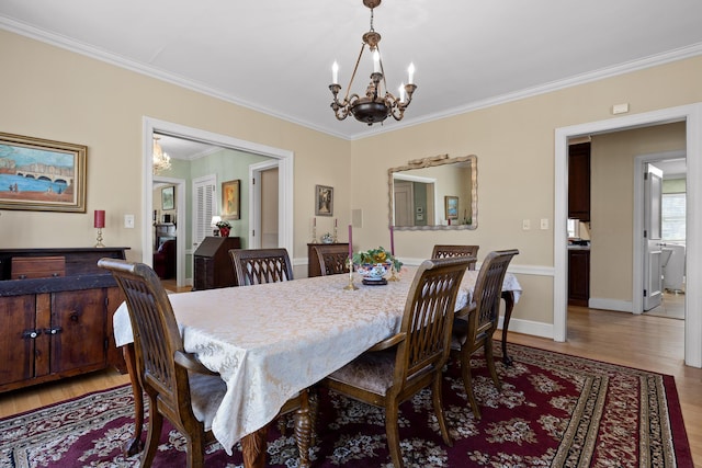 dining room with baseboards, light wood-style floors, a chandelier, and crown molding