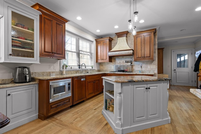 kitchen featuring paneled dishwasher, custom exhaust hood, ornamental molding, a sink, and stainless steel microwave