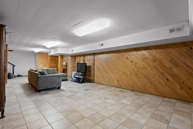 unfurnished living room with visible vents, wood walls, and baseboards