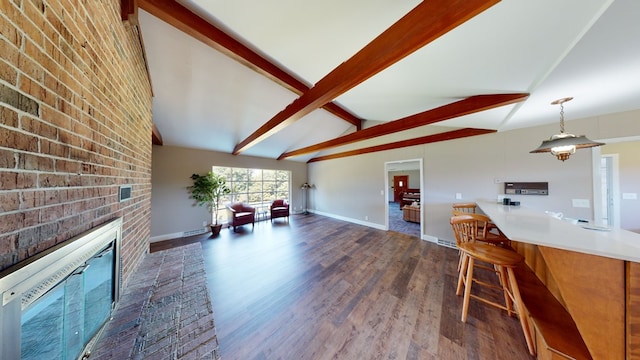 unfurnished living room featuring a fireplace, vaulted ceiling with beams, dark hardwood / wood-style floors, and brick wall