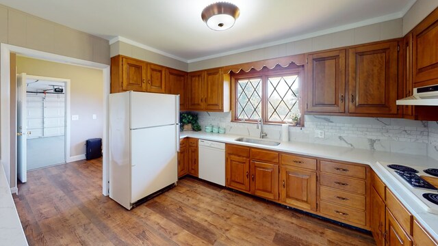 kitchen featuring white appliances, backsplash, crown molding, sink, and hardwood / wood-style flooring