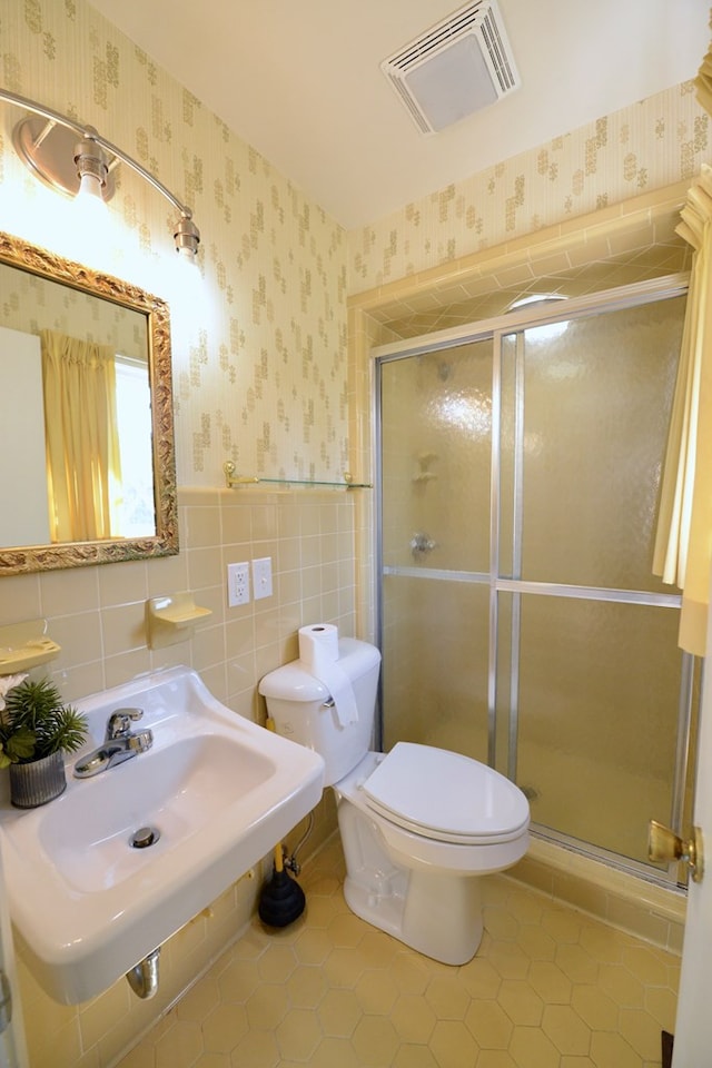 bathroom featuring tile patterned floors, toilet, sink, and walk in shower