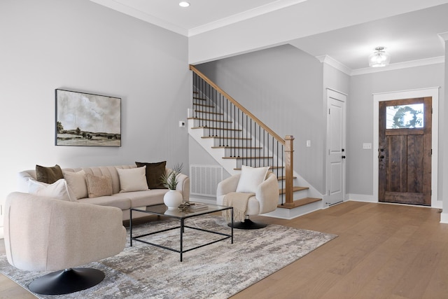 foyer with wood finished floors, visible vents, crown molding, and stairs