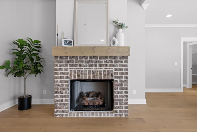 details with baseboards, wood finished floors, crown molding, a brick fireplace, and recessed lighting