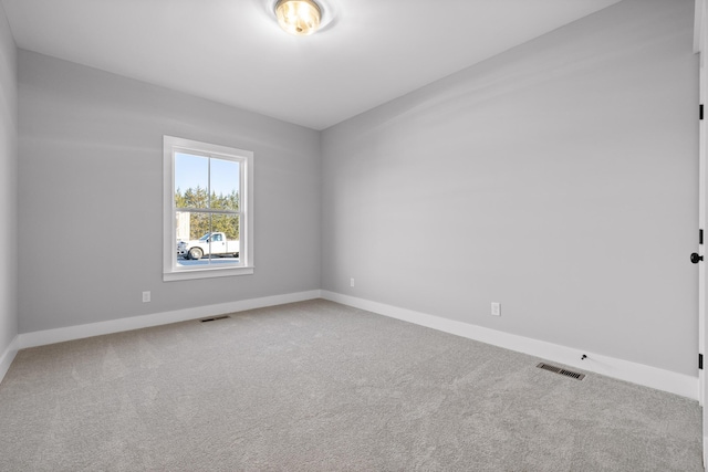 spare room featuring carpet, visible vents, and baseboards