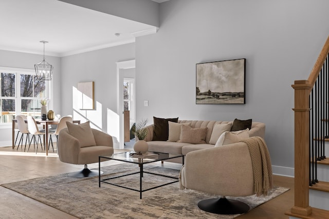 living room featuring a notable chandelier, crown molding, baseboards, and wood finished floors