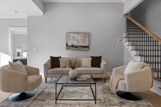 living area featuring stairs, crown molding, baseboards, and wood finished floors