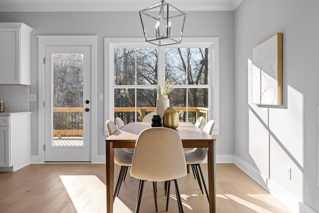 dining space with a chandelier, baseboards, ornamental molding, and light wood finished floors