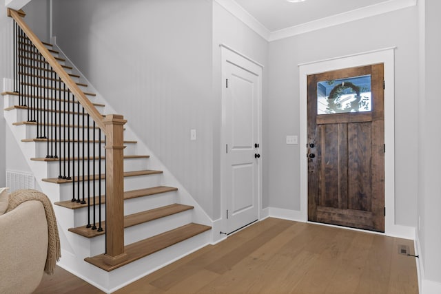 foyer with ornamental molding, stairway, baseboards, and wood finished floors