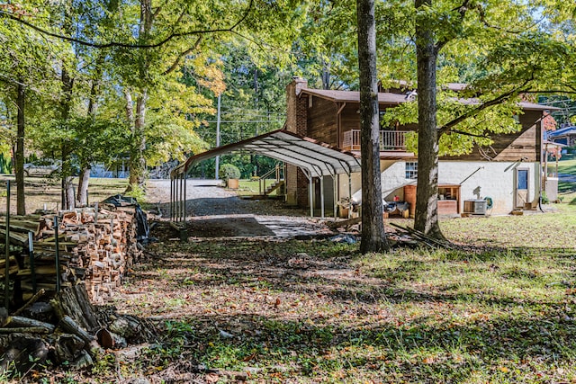 view of yard with a balcony, central AC, and a carport