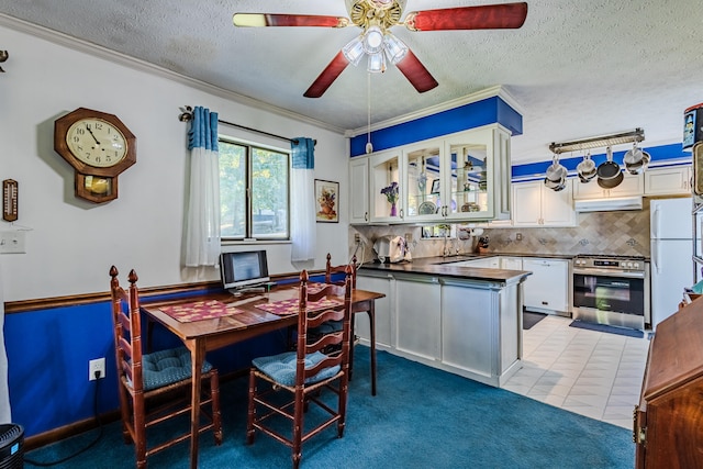 kitchen with ornamental molding, a textured ceiling, light tile patterned floors, stainless steel range oven, and white cabinetry