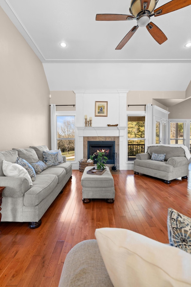 living room featuring a ceiling fan, lofted ceiling, wood-type flooring, and a fireplace