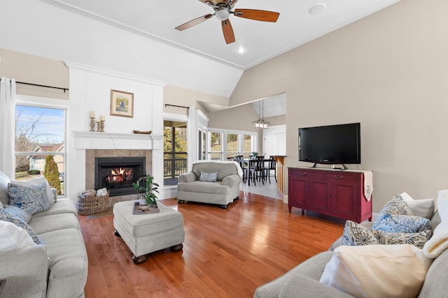 living area featuring high vaulted ceiling, light wood-type flooring, a fireplace, and ceiling fan