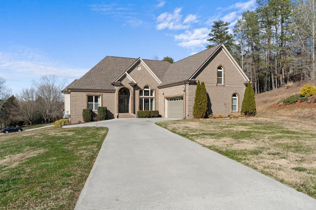 view of front of house featuring driveway, roof with shingles, a front lawn, and brick siding