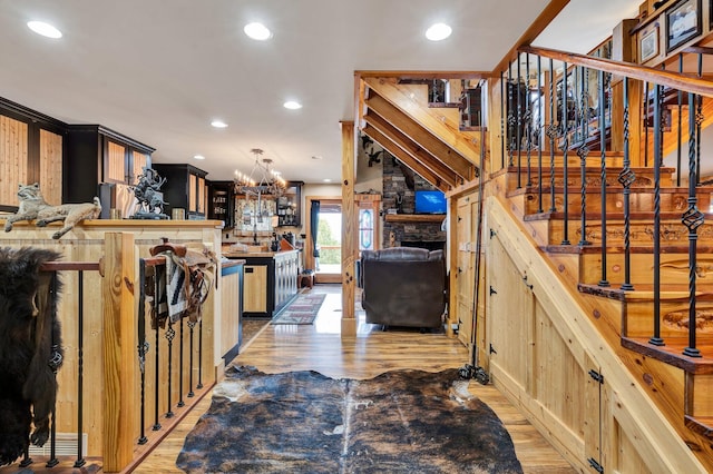 interior space featuring a stone fireplace, a notable chandelier, and light wood-type flooring