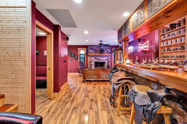 interior space with light wood-type flooring, a stone fireplace, and ceiling fan