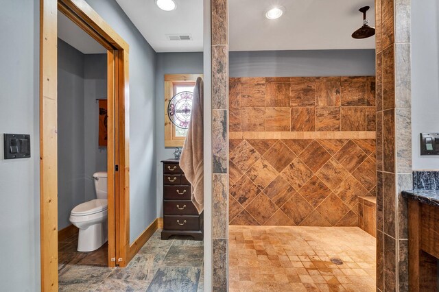 bathroom with a tile shower and toilet